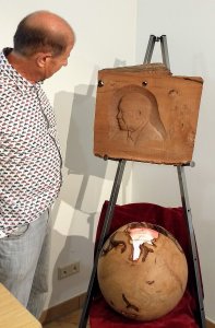 Toni Santa vom Moorlärche Museum aus Südtirol steht im ersten Raum der Moorlärche Ausstellung im Haus der Stadtgeschichte in Hohenmölsen. Er ist im Profil abgebildet und blickt auf das rechts auf einer Staffelei stehende Relief von Nelson Mandela aus braun schimmernden Moorlärche Holz. Mandela ist als ältester Mann abgebildet, seine Büste erscheint im Profil mit Blick nach links. Darunter steht eine Kugel aus Zirbenholz mit Ähnlichkeit zur Erdkugel. Eine Öffnung erinnert an die Umrisse des Kontinents Afrika.